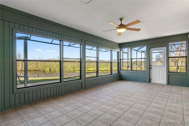 unfurnished sunroom with ceiling fan and a water view