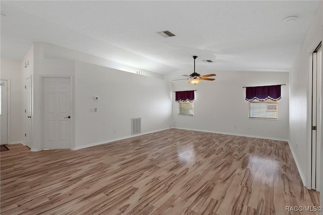 spare room featuring lofted ceiling, light wood-type flooring, visible vents, and ceiling fan