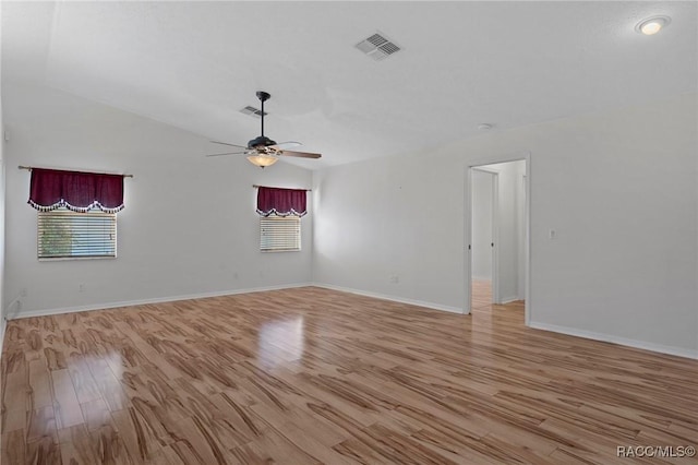 empty room featuring lofted ceiling, a ceiling fan, baseboards, visible vents, and light wood-style floors