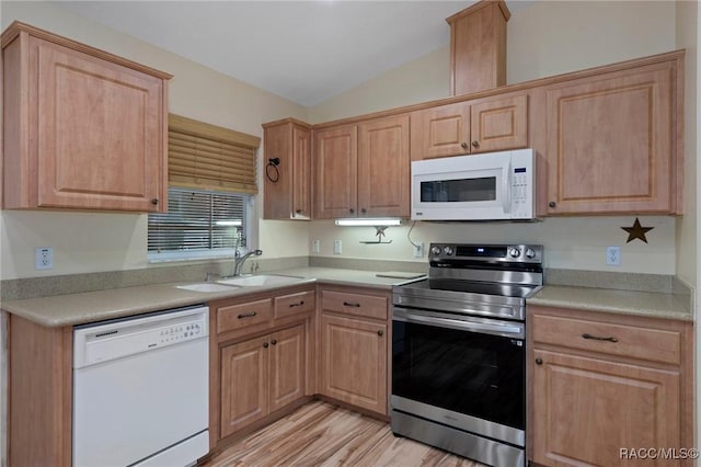 kitchen featuring lofted ceiling, white appliances, light brown cabinets, and a sink