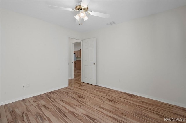 empty room with baseboards, visible vents, ceiling fan, and light wood finished floors