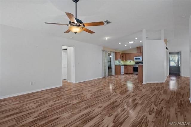 unfurnished living room featuring lofted ceiling, light wood finished floors, visible vents, and a ceiling fan