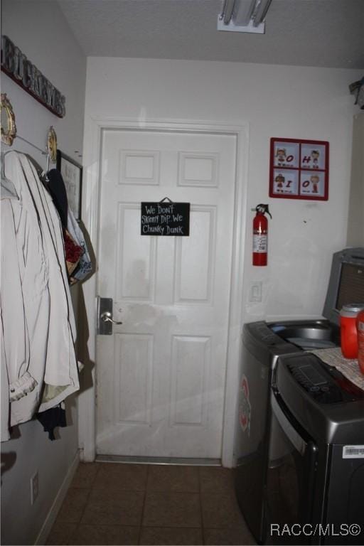 clothes washing area with dark tile patterned floors and washer and clothes dryer