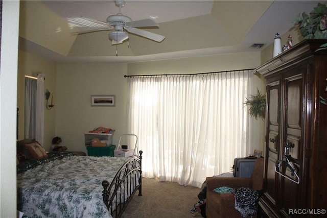 carpeted bedroom featuring a raised ceiling and ceiling fan