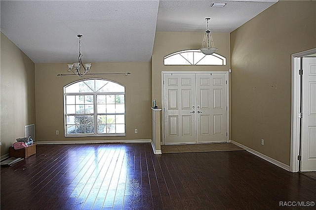 entryway with baseboards, hardwood / wood-style floors, vaulted ceiling, and an inviting chandelier