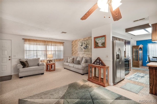 living area with visible vents, ceiling fan, and carpet flooring