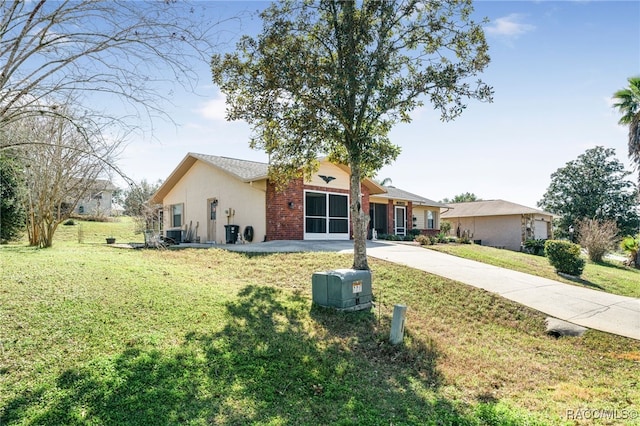 ranch-style house with driveway, brick siding, a front yard, and stucco siding