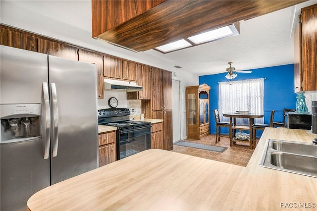 kitchen featuring a ceiling fan, black electric range oven, light countertops, under cabinet range hood, and stainless steel refrigerator with ice dispenser