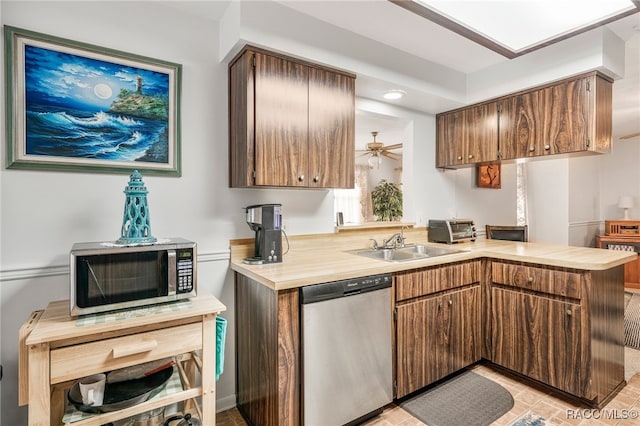 kitchen with ceiling fan, stainless steel appliances, a peninsula, a sink, and light countertops