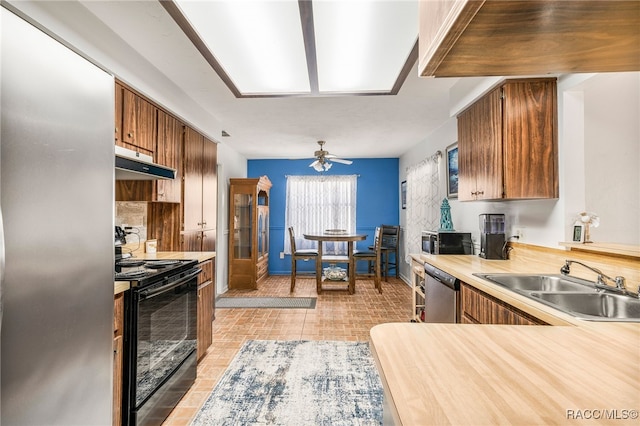 kitchen with under cabinet range hood, stainless steel appliances, a sink, a ceiling fan, and light countertops