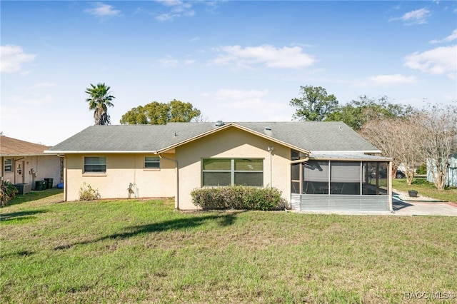 rear view of property featuring a sunroom, a yard, and stucco siding