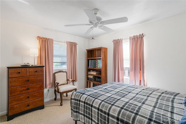 bedroom with light colored carpet, multiple windows, ceiling fan, and baseboards