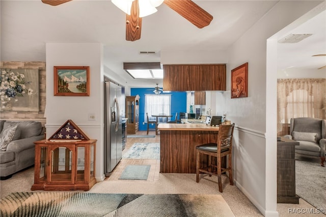 kitchen with a peninsula, ceiling fan, open floor plan, and stainless steel fridge with ice dispenser