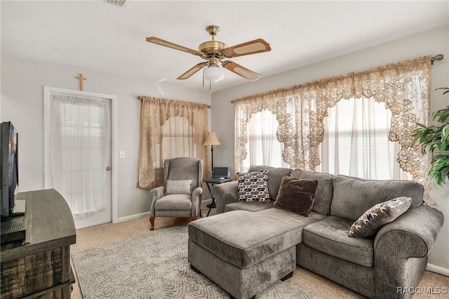 living area with a ceiling fan, light colored carpet, and baseboards