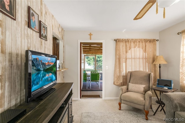 sitting room featuring baseboards, a ceiling fan, and light colored carpet