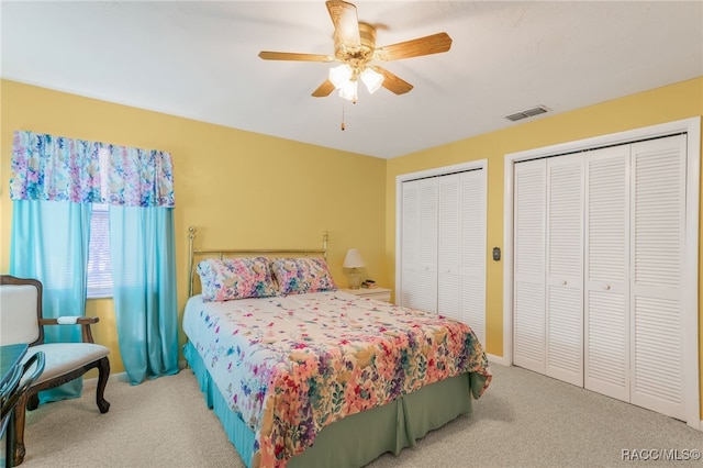 bedroom featuring carpet floors, a ceiling fan, baseboards, visible vents, and multiple closets