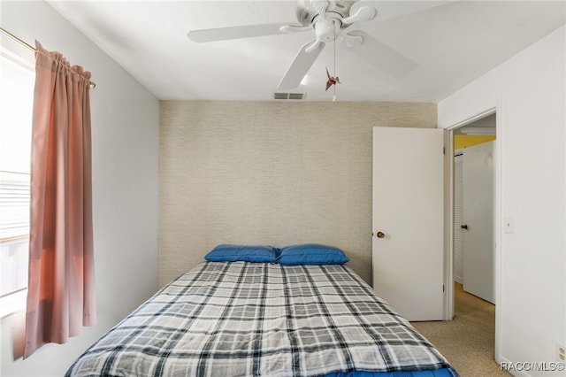 bedroom with visible vents, a ceiling fan, and light colored carpet