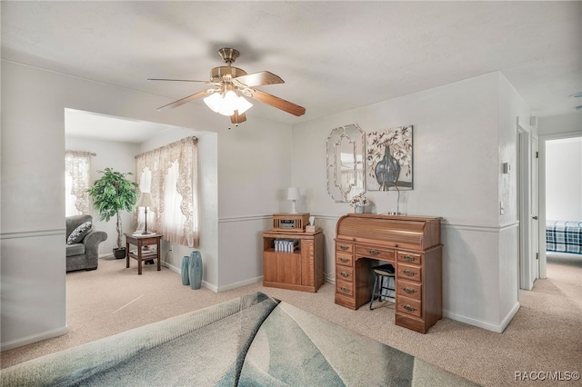 office area featuring light carpet, baseboards, and a ceiling fan