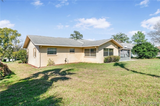 back of house featuring a sunroom, a yard, and stucco siding