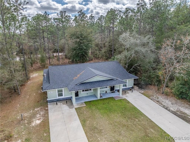 9459 N Camel Dr, Citrus Springs, FL 34434 - view of front facade featuring concrete driveway, a shingled roof, a front lawn, stucco siding, and covered porch