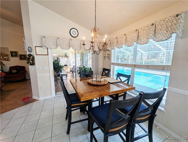 tiled dining space with lofted ceiling and an inviting chandelier