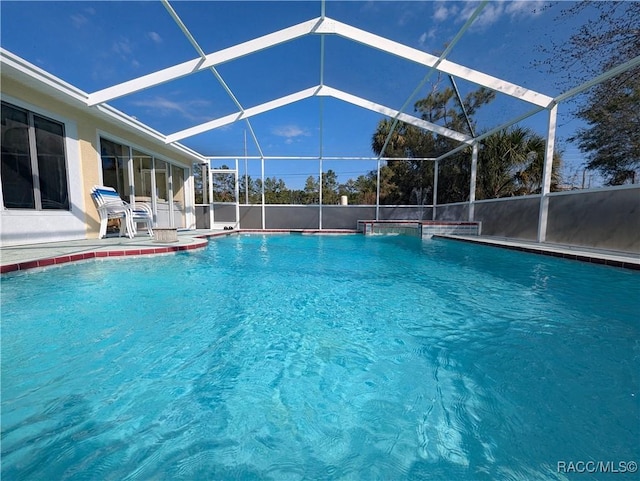 view of pool featuring pool water feature, glass enclosure, and a patio area