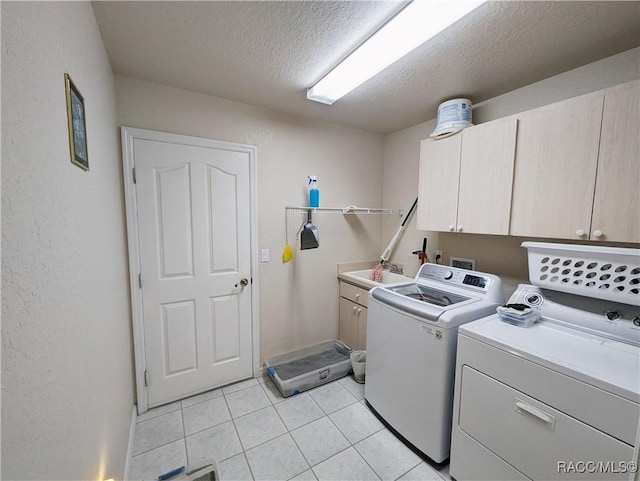 clothes washing area with sink, cabinets, washer and clothes dryer, light tile patterned floors, and a textured ceiling