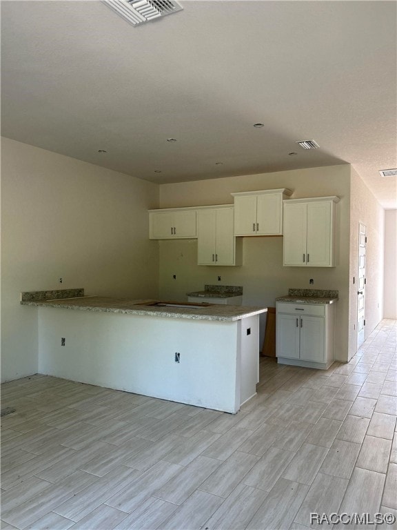 kitchen featuring white cabinets, light wood-type flooring, and a kitchen island