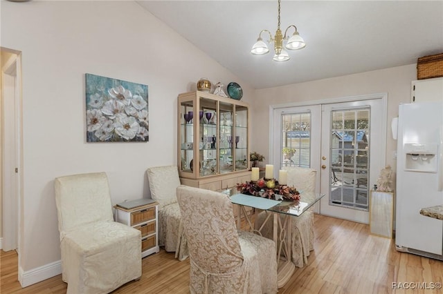 dining room featuring vaulted ceiling, a chandelier, light hardwood / wood-style floors, and french doors