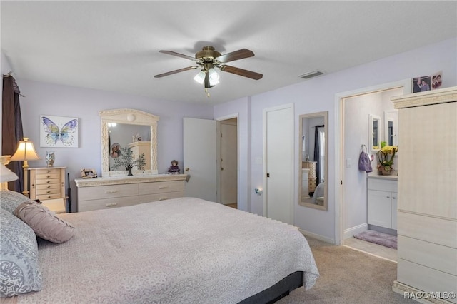 bedroom featuring ensuite bathroom, light carpet, and ceiling fan