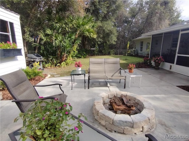 view of patio / terrace featuring a grill, a sunroom, and a fire pit