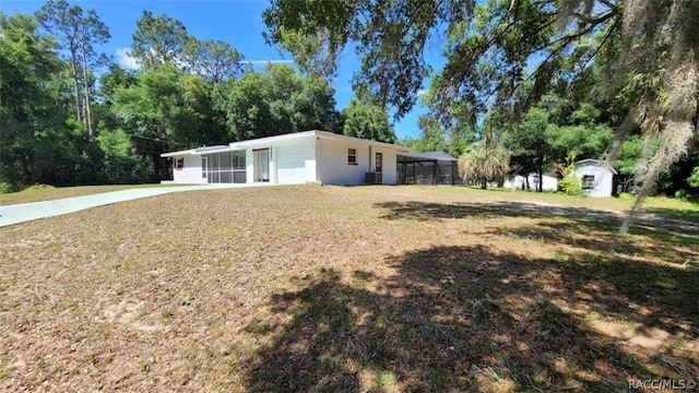 single story home with a lanai, a storage shed, and a front yard