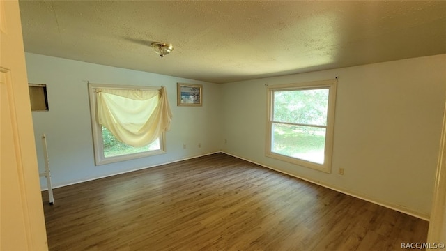 spare room featuring dark hardwood / wood-style floors and a textured ceiling