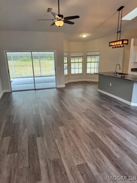 unfurnished living room featuring sink, dark wood-type flooring, and ceiling fan