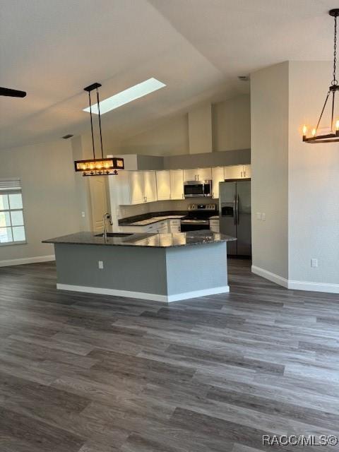 kitchen with dark wood-type flooring, appliances with stainless steel finishes, sink, and hanging light fixtures