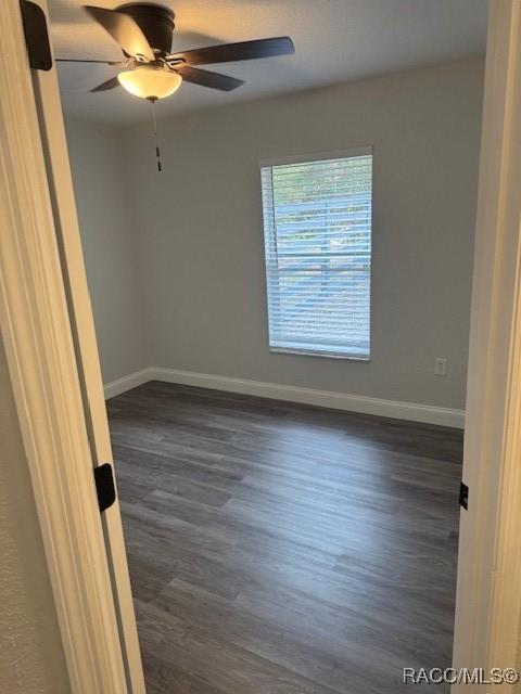 empty room with dark wood-type flooring and ceiling fan