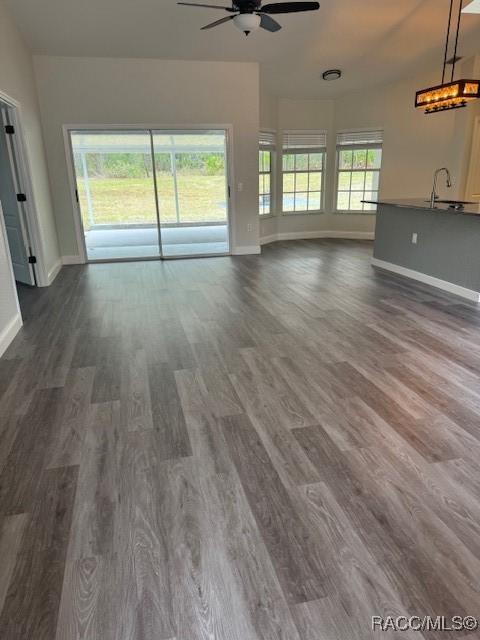 unfurnished living room featuring ceiling fan, sink, and hardwood / wood-style floors