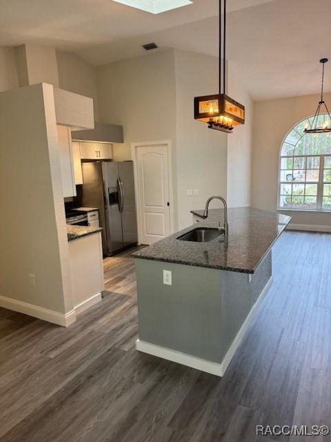 kitchen with pendant lighting, sink, dark stone countertops, white cabinets, and stainless steel fridge with ice dispenser