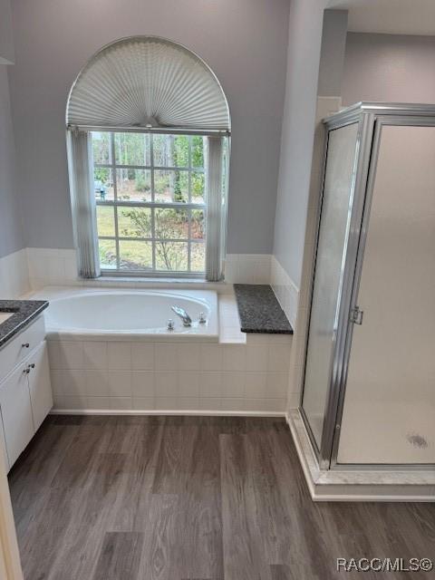 bathroom with hardwood / wood-style flooring, shower with separate bathtub, and vanity