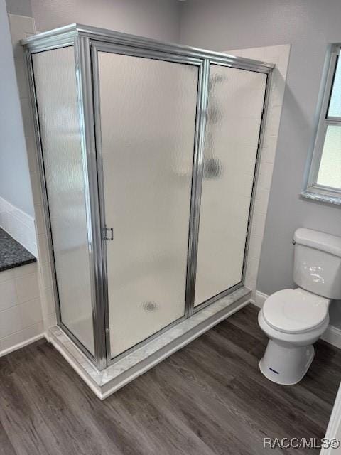 bathroom featuring hardwood / wood-style flooring, toilet, and walk in shower