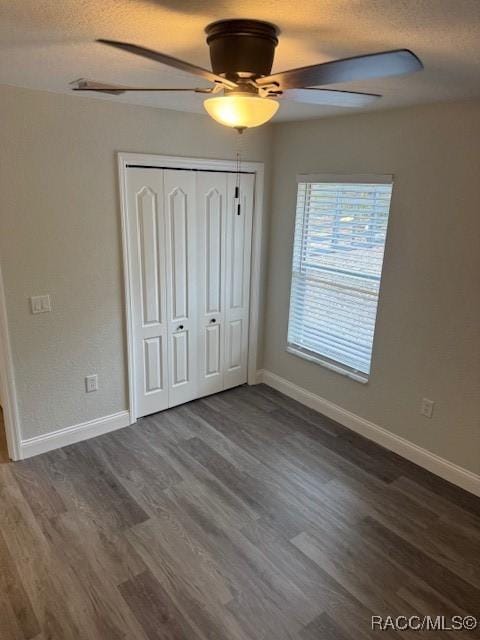 unfurnished bedroom with a closet, dark hardwood / wood-style floors, a textured ceiling, and ceiling fan