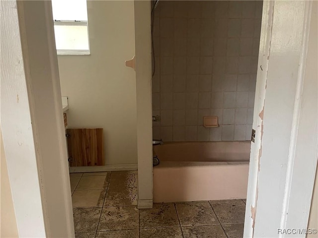 bathroom featuring tiled shower / bath combo and tile patterned flooring