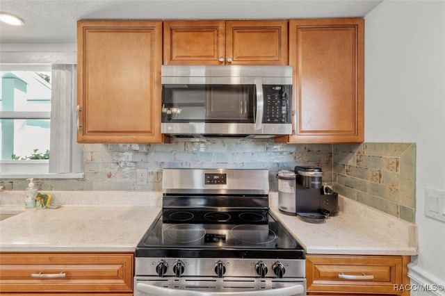 kitchen with backsplash, light stone counters, and stainless steel appliances