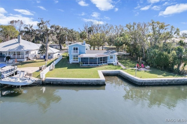 back of house featuring a sunroom, a water view, and a lawn