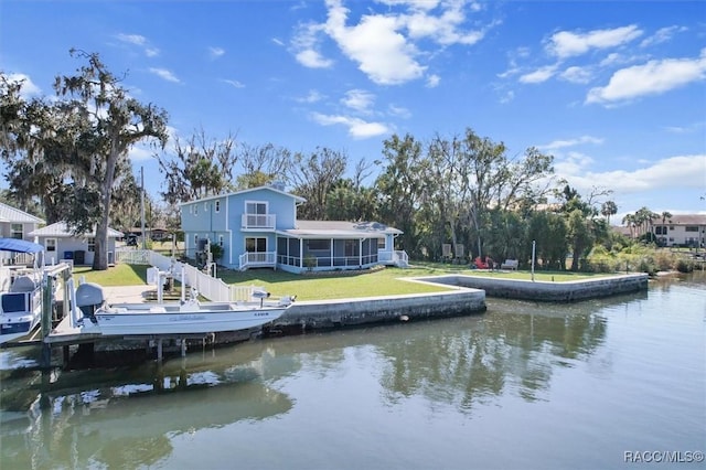 rear view of property with a sunroom, a water view, and a yard