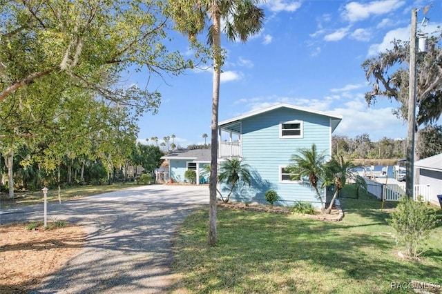 view of side of property featuring a balcony and a lawn