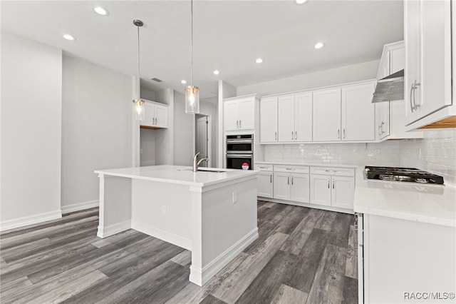 kitchen with white cabinetry, an island with sink, dark wood-type flooring, and decorative light fixtures