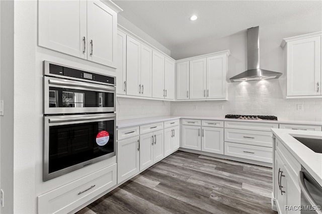 kitchen featuring white cabinets, wall chimney exhaust hood, stainless steel appliances, and dark hardwood / wood-style floors