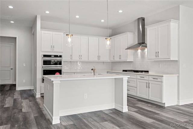 kitchen featuring wall chimney exhaust hood, stainless steel appliances, dark wood-type flooring, hanging light fixtures, and white cabinets