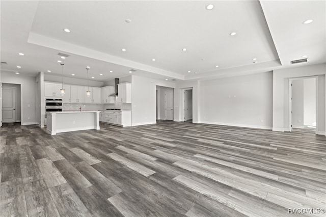 unfurnished living room with a raised ceiling and light wood-type flooring